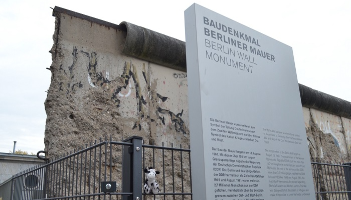 Colour photo from the Berlin Wall Memorial in Germany. It shows a remaining section of the wall and a display explaining the history in German and English.