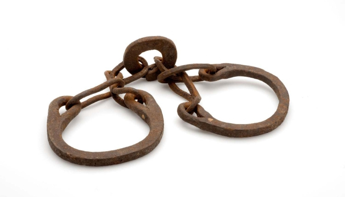 Image: Slave shackles (COLLECTIE TROPENMUSEUM IJzeren voetring voor gevangenen TMnr 3912-475.jpg) by Collectie Wereldmuseum (v/h Tropenmuseum), part of the National Museum of World Cultures, on Wikimedia Commons. CC BY-SA 3.0 (https://creativecommons.org/licenses/by-sa/3.0/deed.en). Image cropped.
