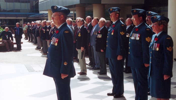 Colour photo of war veterans standing beside the Takapuna War memorial during its official dedication on 11 November 2002.