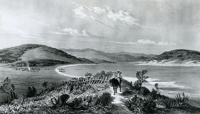 Black and white illustration of a man on horseback looking towards Taupō Kāinga (village) on the shore. There is an inlet and mountains in the background.