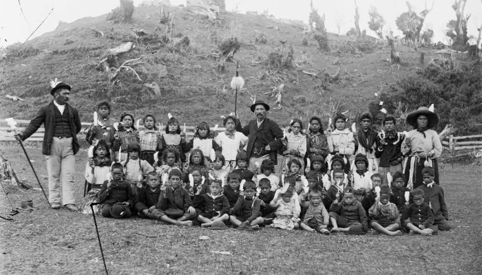 Black and white photo showing a group of people from Parihaka Pā, including children and Taare Waitara.