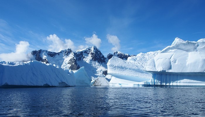 Colour photo from Antarctica showing glaciers, ice mountains and blue ocean.