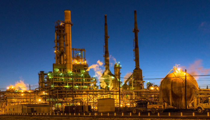 Colour photo of an oil refinery at Port Arthur in Texas showing rocket-shaped structures and lots of pipes.