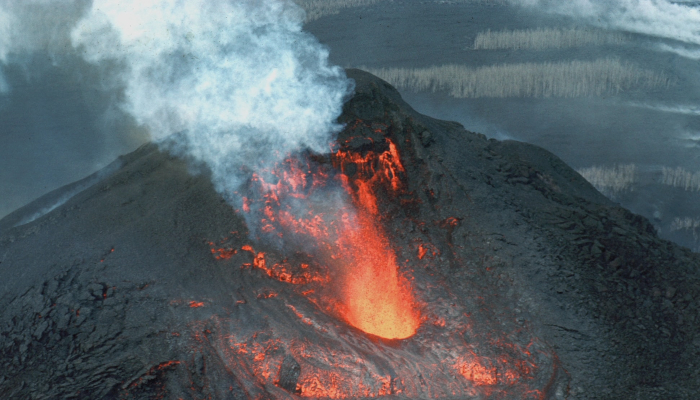 Colour photo of the top of Kilauea Volcano, Hawaii. The centre of the volcano is red with lava — everything around it is black.