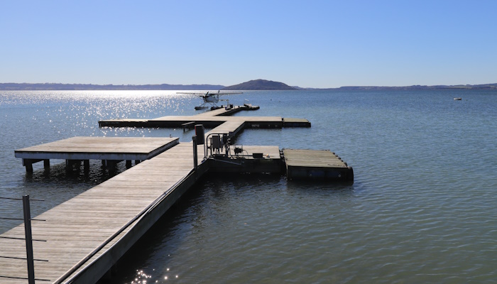 Colour photo of Lake Rotorua. In the foreground is a wharf. Mokoia Island can be seen in the background.