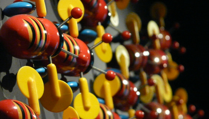 Colour photo of many Buzzy Bee toys on display — a popular Aotearoa NZ toy. It shows their red, yellow and black bodies, yellow wings and blue wheels.