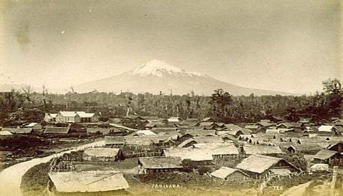 Black and white photo of Parihaka showing the whare (houses) and Taranaki Maunga (Mount Egmont) in the background.