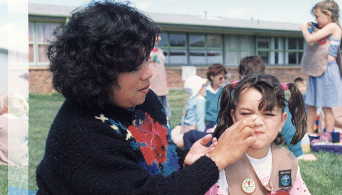 Colour photo from 1991 of a woman putting sunscreen on a girl's face.