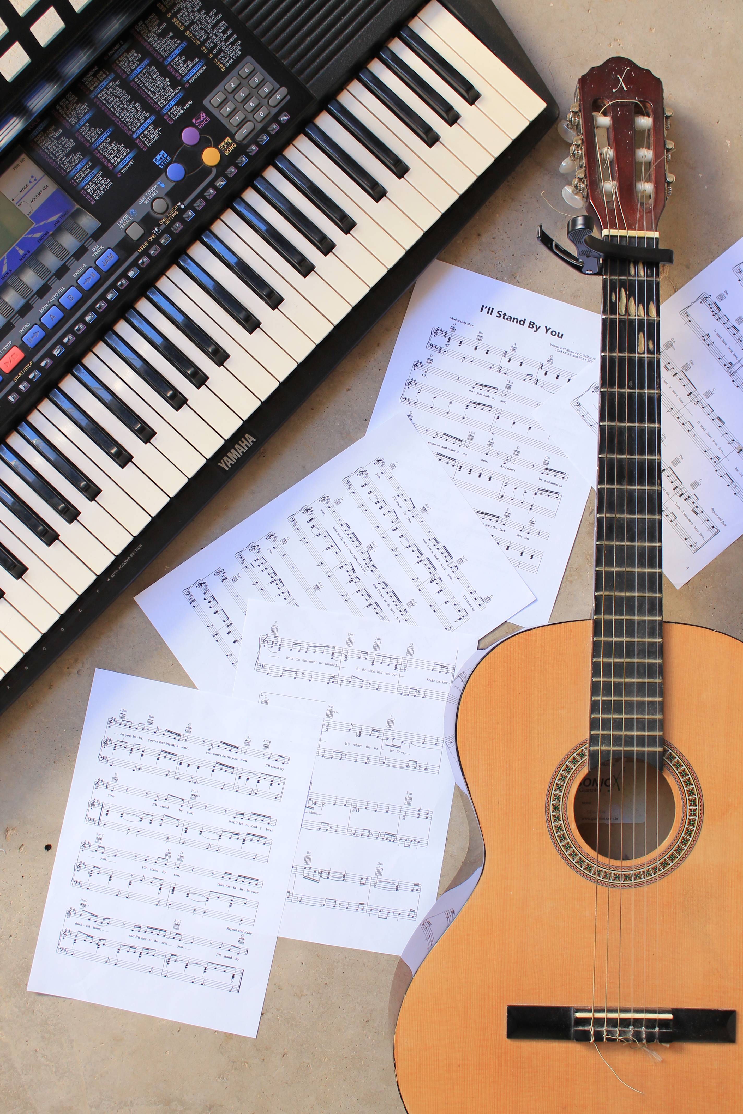 Colour photo of a guitar, keyboard, and some sheet music for "I'll Stand By You".