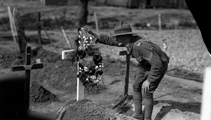 Image: New Zealand soldier stands over the grave of a fallen comrade (https://www.flickr.com/photos/nationallibrarynz_commons/21499695860/) by Henry Armytage from National Library NZ on The Commons on Flickr.