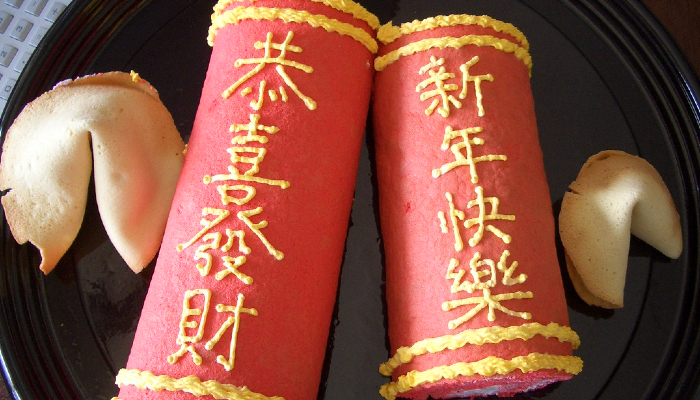 Colour photo of food celebrating Chinese New Year. It shows 2 cakes with writing in Chinese and 2 fortune cookies.