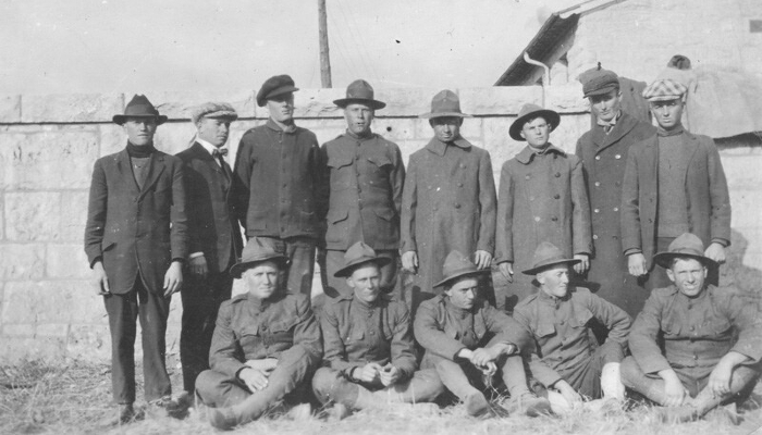 Black and white photo of conscientious objectors (COs) at Fort Riley, a United States Army base. Some COs are in civilian clothing, and the others are in military uniform.