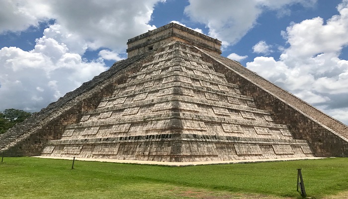 Colour photo of El Castillo, an ancient limestone pyramid built by the Mayans in Mexico. Staircases on each side lead to a temple at the top.