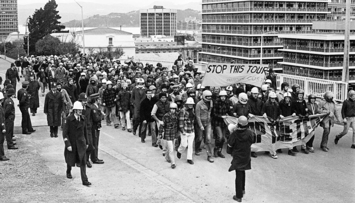 1981 black and white photo of Springbok Tour protestors on Hill Street, Wellington. Police are alongside.
