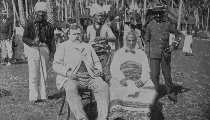 1900 photo showing Premier Richard Seddon and King Togia of the Savage Islands (now Niue) seated. 3 guards stand behind them.