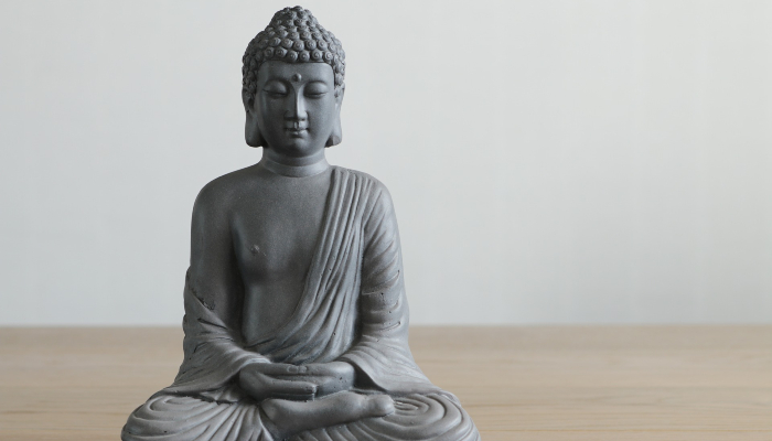 Colour photo of a Buddha statue sitting with legs crossed and hands interlocked.