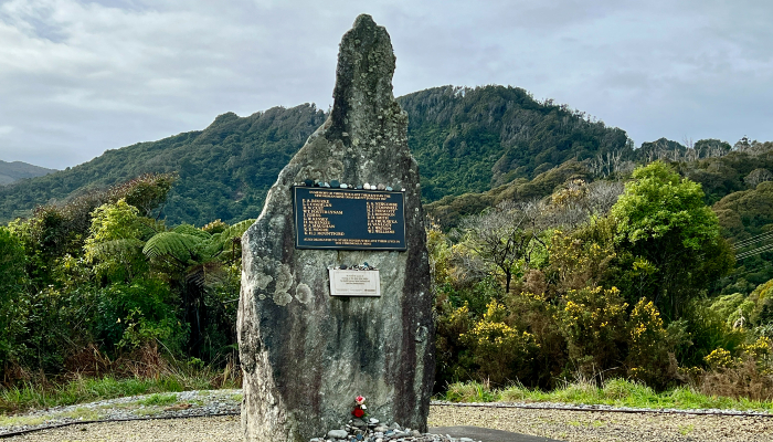 Colour photo showing the Strongman Mine Disaster memorial near Rapahoe, West Coash, Aotearoa NZ. A plaque on the stone memorial remembers the 19 lives lost in the 1967 disaster.