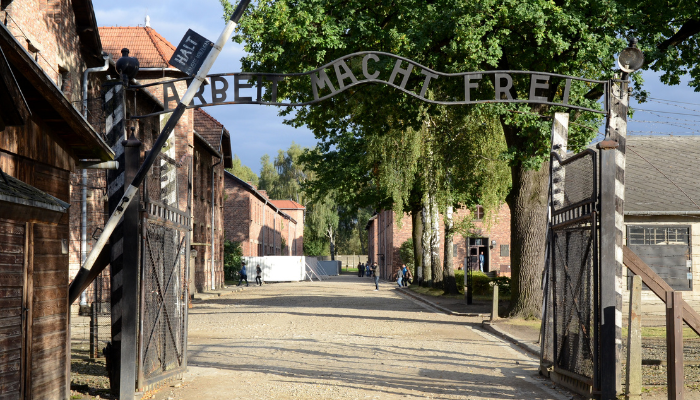2012 photo of a gate to Auschwitz Concentration Camp. A sign on the gate says "Arbeit Macht Free" meaning "Work sets you free".