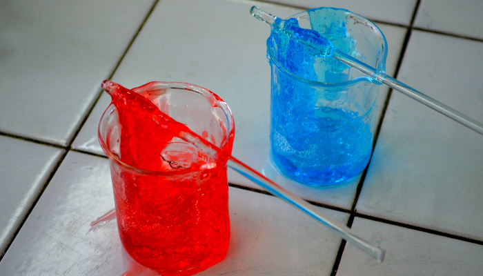 Colour photo of two beakers with stirring rods across the top. One beaker has red slime, the other has blue slime.