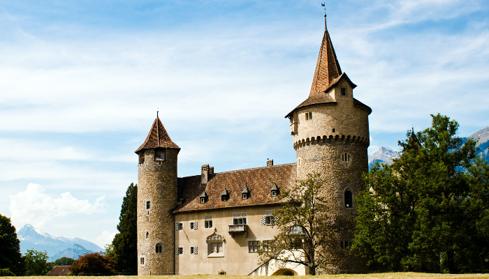 Colour photo of the Marschlins Castle in Switzerland. It shows a side of the castle with 2 round towers on either end.