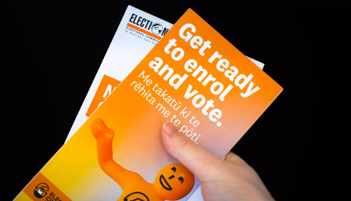 Colour photo of a hand holding 'Get ready to enrol and vote' fliers from the 2022 local elections in Christchurch, Aotearoa NZ.