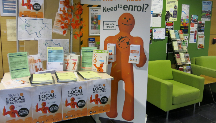 Colour photo of a display with fliers and posters with voting information for the 2016 local elections in Christchurch, Aotearoa NZ.