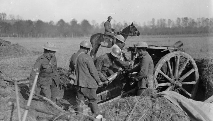 1918 black and white photo of a group of Aotearoa NZ soldiers loading a 4.5 howitzer near Le Quesnoy, France.