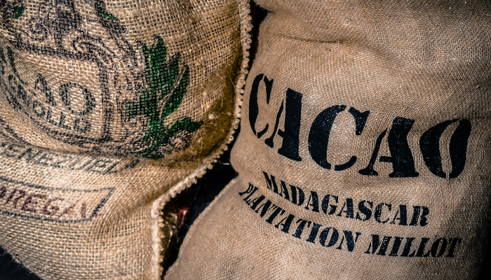 Colour photo of 2 labelled burlap bags — one reads 'Cacao — Madagascar plantation millot'.
