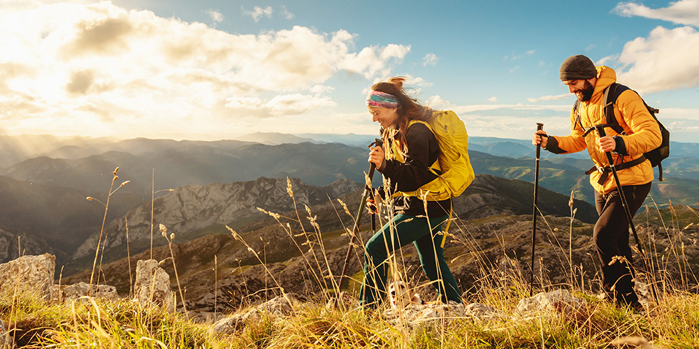 man and and woman hikers trekking up mountain