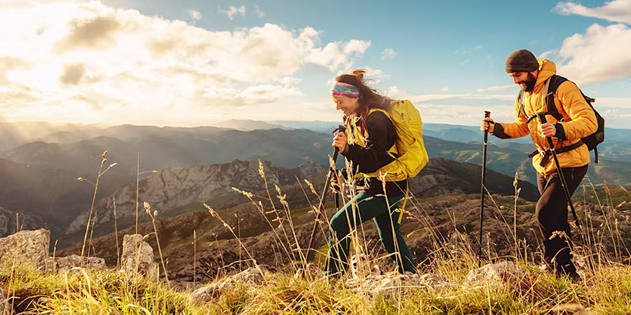 man and and woman hikers trekking up mountain