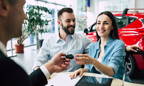 Couple in car dealership getting handed car keys