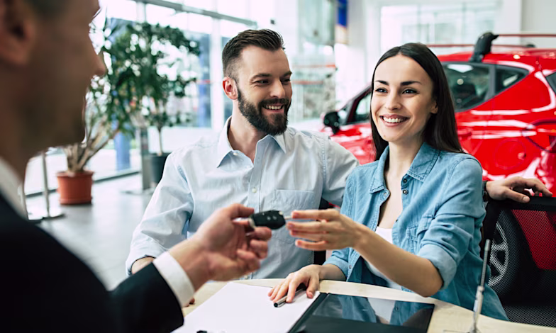 Couple in car dealership getting handed car keys