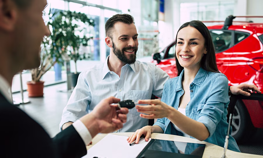 Couple in car dealership getting handed car keys