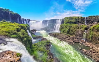 Foz do Iguacu Iguazu Falls waterfall fall waterfalls cascade cascades in tropical nature rainforest panorama view with blue sky and turquoise green water in Parana Brazil and Misiones Argentina.
