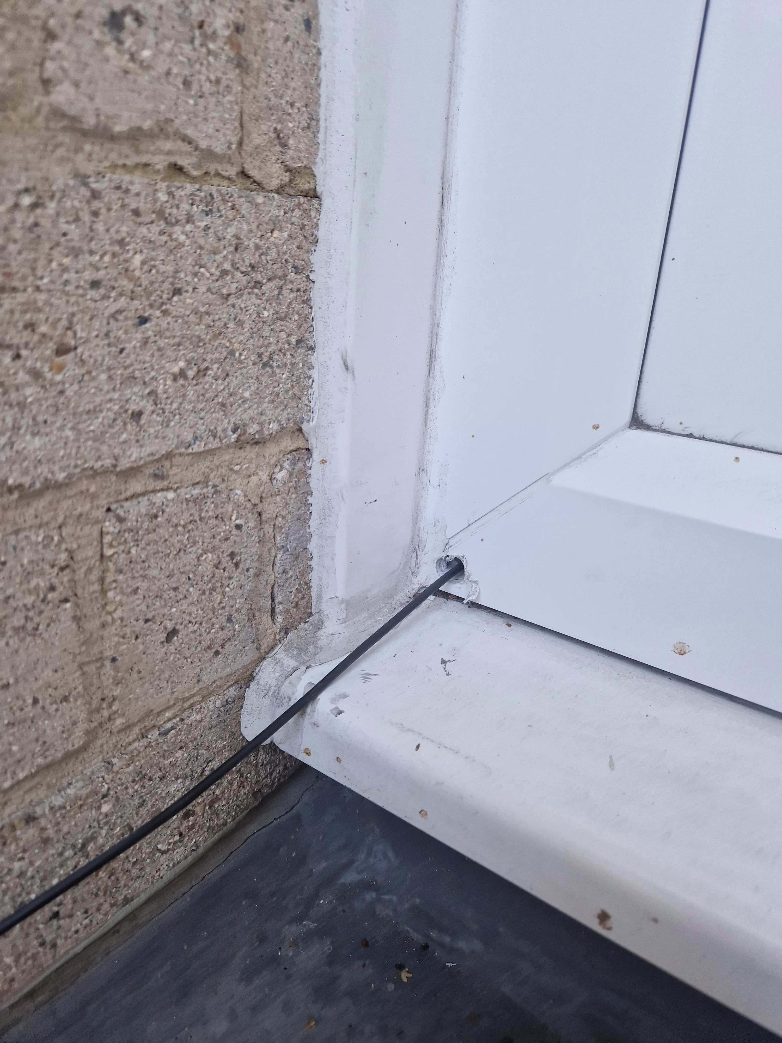 A small FTTP cable running into a balcony door frame