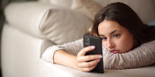 young woman looking at phone lying down