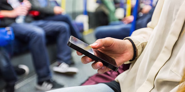man looking at phone on train