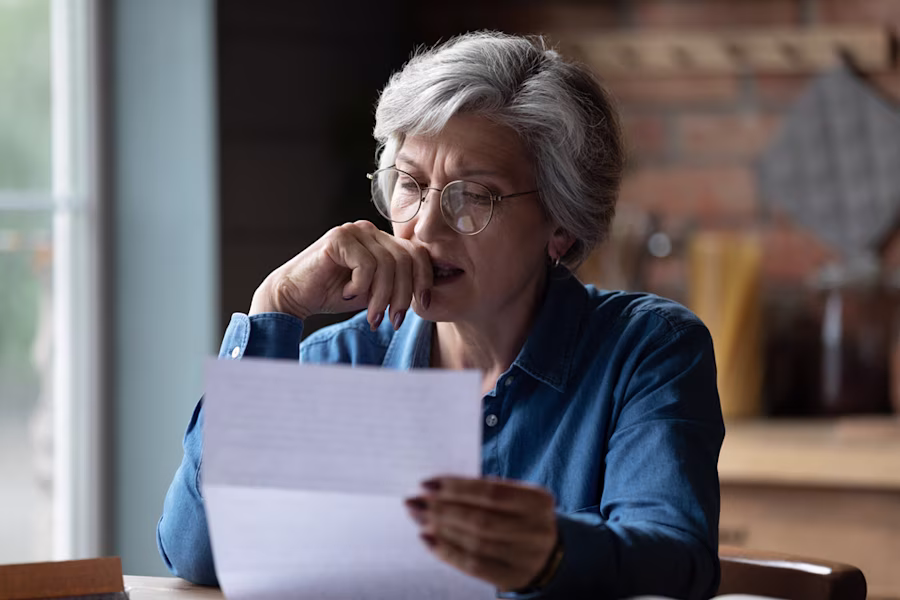 Upset older woman reading paperwork