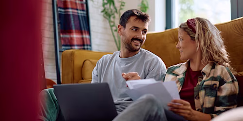couple on laptop conversing with documents
