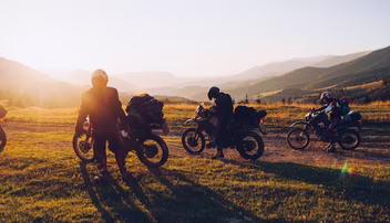 People on motorbikes on a hill with a sunset in the background