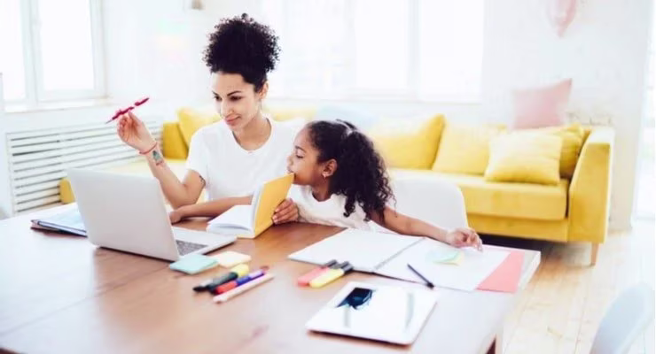A woman works from home while helping her child with her studies