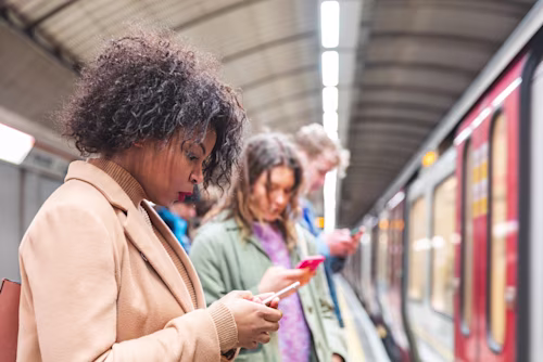 commuters on a train platform using their mobile phones