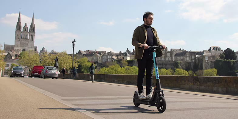 Young man riding electric scooter on road