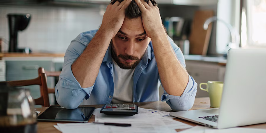 man sat at table with documents appearing stressed