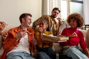 multiracial group of young people at house party eating pizza and drinking beer and having fun 