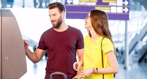 a couple using a foreign exchange machine at an airport