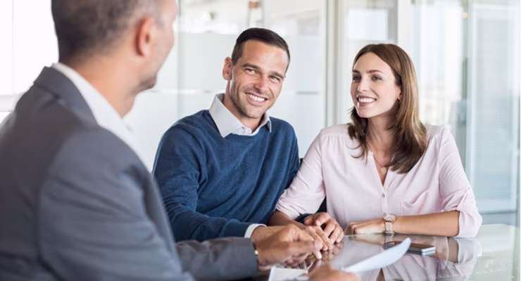 A couple in an office listen to their financial advisor across the desk