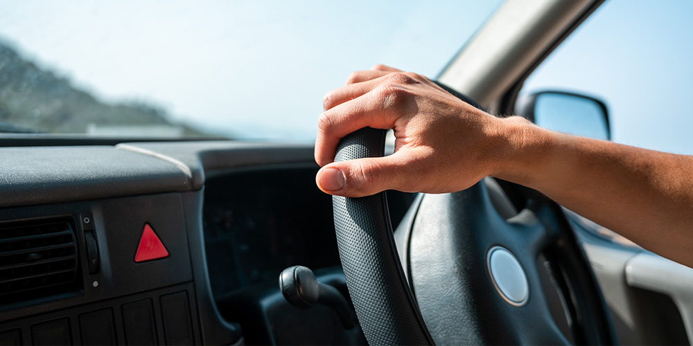 hand holding steering wheel on sunny day