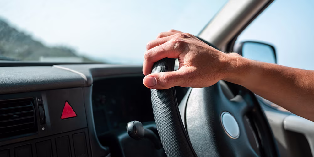 hand holding steering wheel on sunny day