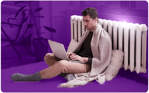 Man leaning against a radiator with a laptop